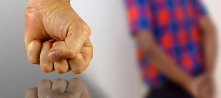 Puño cerrado en señal de advertencia, con mujer en segundo plano.