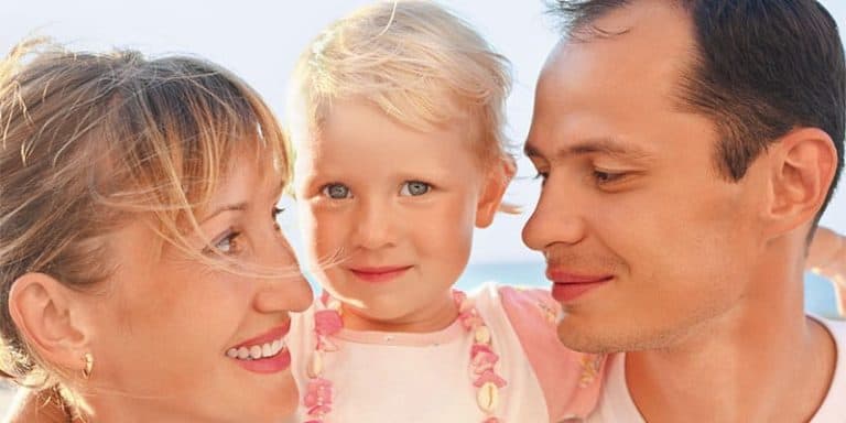Imagen de una familia feliz con un niño pequeño y sus padres sonriendo juntos.