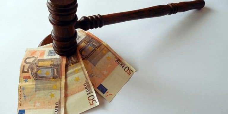 Imagen de un martillo de juez sobre billetes de 50 euros, representando costas judiciales.