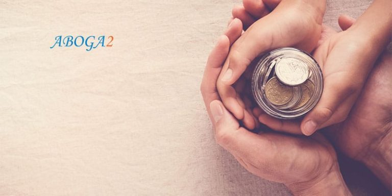 Manos sosteniendo una alcancía con monedas, simbolizando herencias y donaciones.