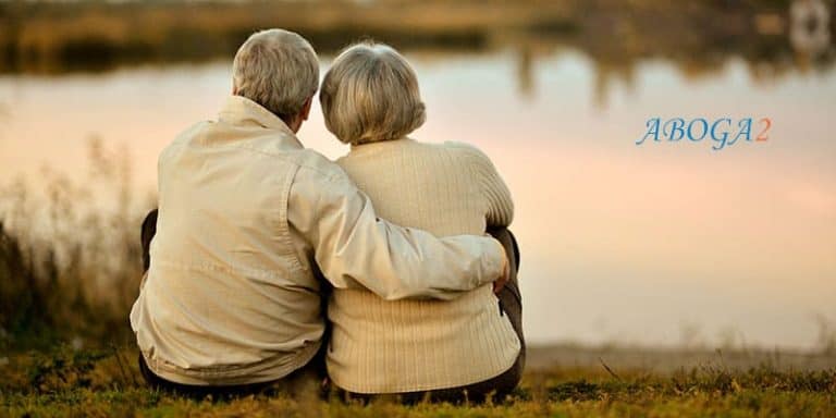 Pareja de ancianos sentados junto al río, simbolizando la herencia y la planificación familiar.