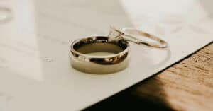 Anillos de boda sobre papel de boda, simbolizando separación de bienes o capitulaciones.
