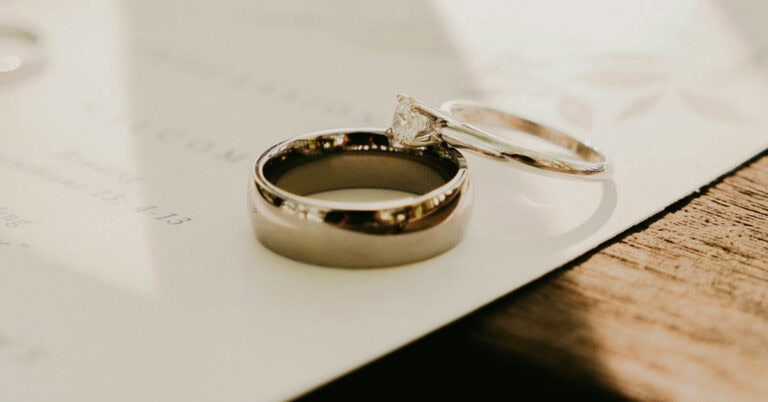 Anillos de boda sobre papel de boda, simbolizando separación de bienes o capitulaciones.