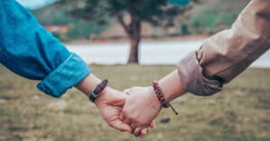 Amor y amistad entre dos personas tomadas de la mano en un entorno natural al aire libre.