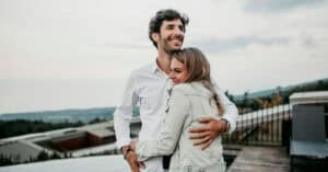Pareja feliz abrazándose en terraza con vista panorámica.