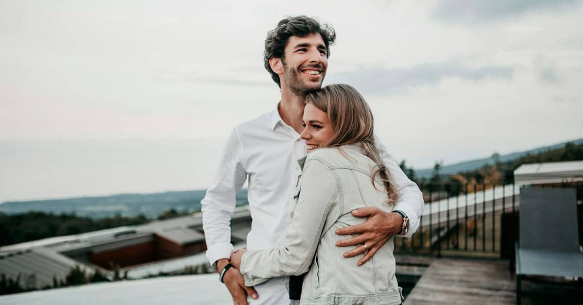 Pareja feliz abrazándose en terraza con vista panorámica.