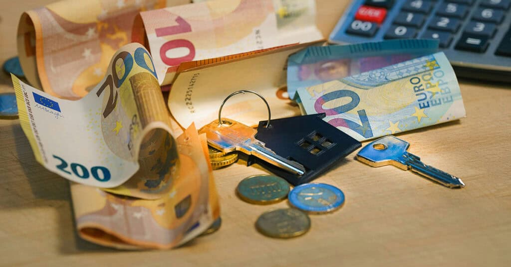 Dinero en euros, llaves y calculadora en mesa de estudio.