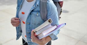 Joven estudiante con libros y mochila en la calle.