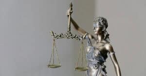 Escultura de la Justicia con balanza y espada, símbolo de equidad legal.
