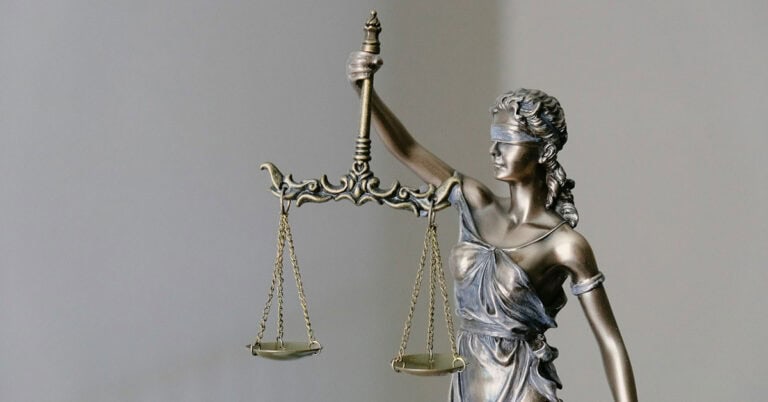 Escultura de la Justicia con balanza y espada, símbolo de equidad legal.