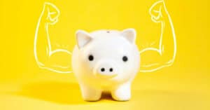 Cerdito de cerámica con músculos dibujados en fondo amarillo.