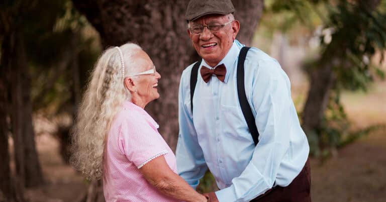 Ancianos felices en un parque, sonriendo y disfrutando del momento.